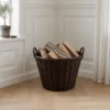 Brændekurv i flet med brænde Stor brændekurv i natur brun flet fyldt med brænde i lys og nordisk indretning.